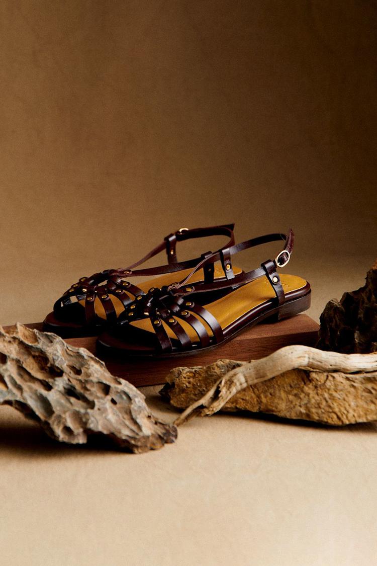 Sandalias color tierra con tiras entrelazadas y tachuelas metálicas doradas, plana
