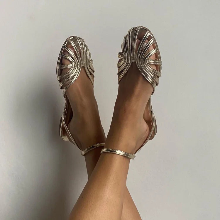 Sandalias de mujer plateadas con tiras cruzadas y pulsera ajustable en el tobillo.