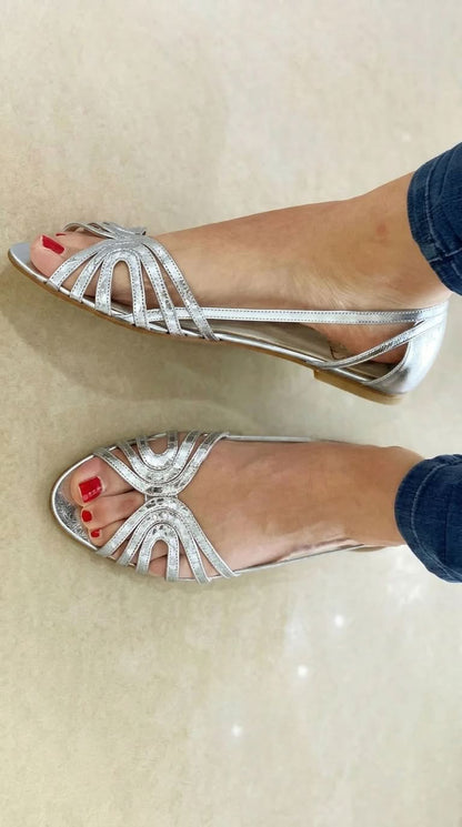 Sandalias plateadas con tiras decorativas tipo abanico y punta abierta, tacón bajo.
