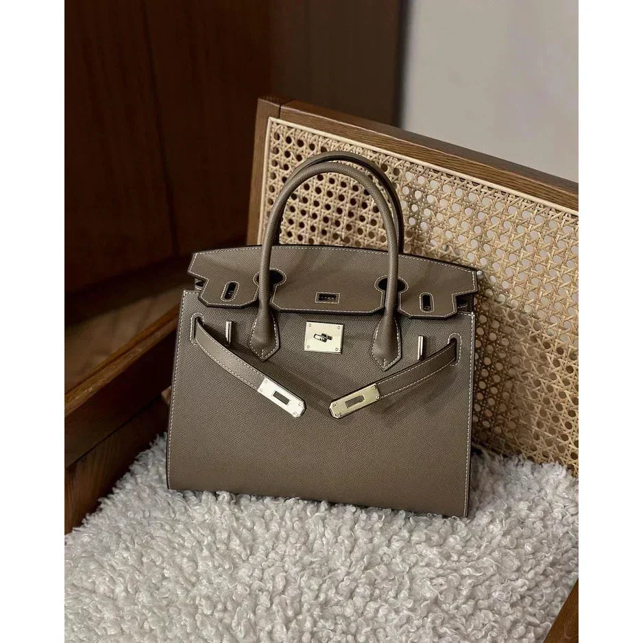 Bolso con reparticiones gris con asas y cierre frontal tipo broche rectangular