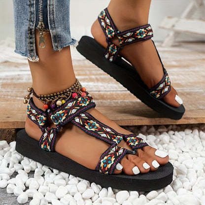 Sandalias ortopédicas negras con tiras multicolor y adorno de cuentas en el tobillo.