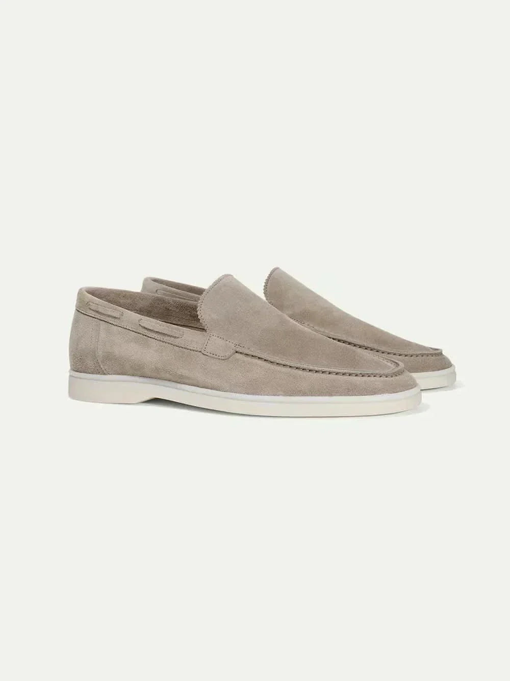 Mocasines de ante color beige topo, estilo slip-on, suela blanca y costuras.