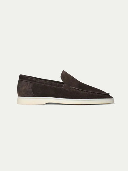 Mocasín de ante café con suela blanca, diseño tipo alpargata y lengüeta sin cordones.