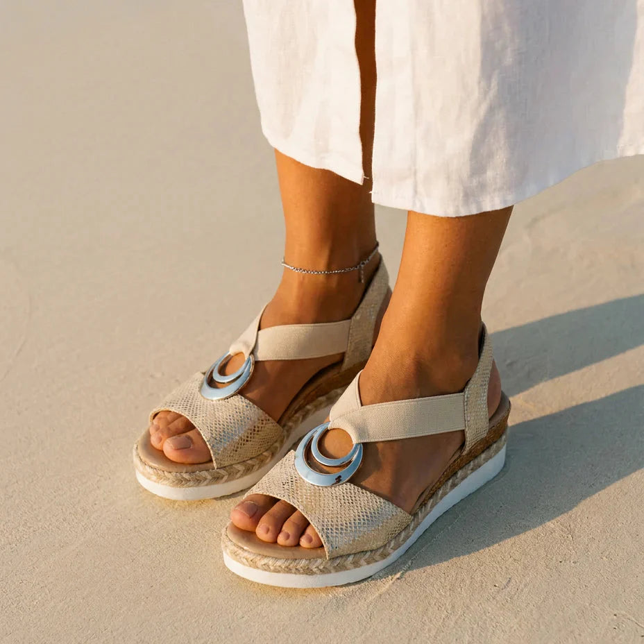 Sandalia ortopédica beige con hebilla plateada, suela de cuña con base blanca