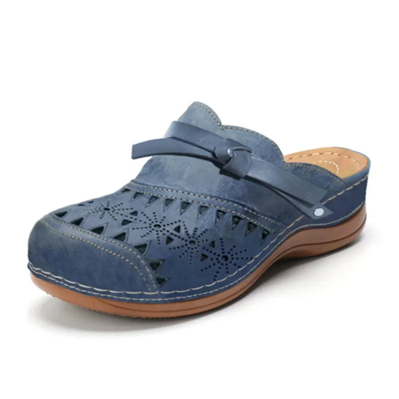 Zueco ortopédico azul oscuro con perforaciones, tira ajustable y suela de cuña marrón