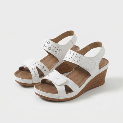 Sandalias ortopédicas blancas con perforaciones, cierre al tobillo y cuña de madera