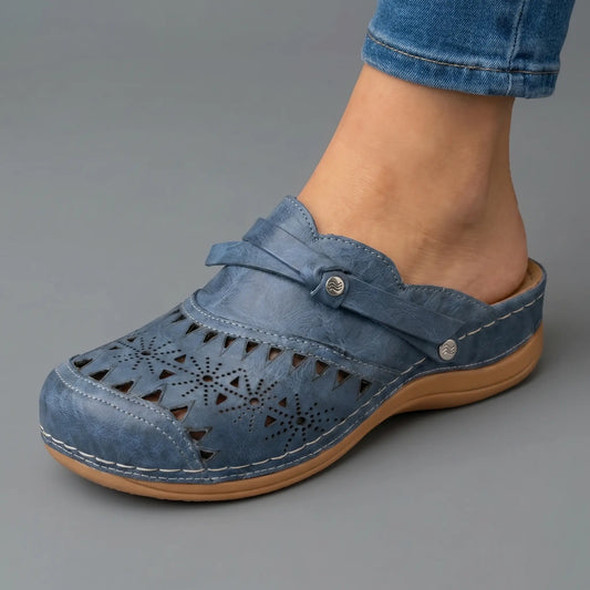 Zueco ortopédico azul con perforaciones, tira ajustable y suela con cuña marrón