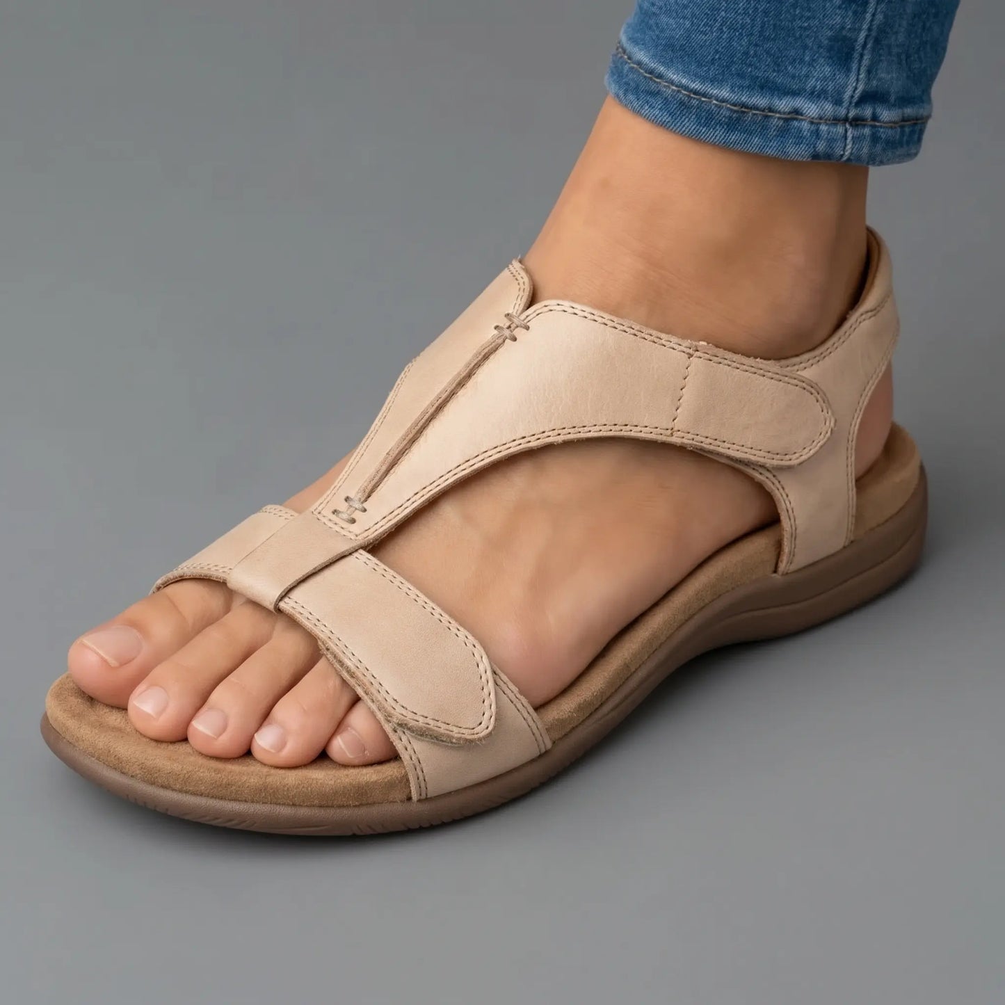 Sandalias ortopédicas beige de piel con tira ajustable al tobillo y suela acolchada.