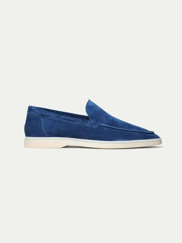 Mocasín de ante azul marino con suela blanca, pala lisa y acabado mate.