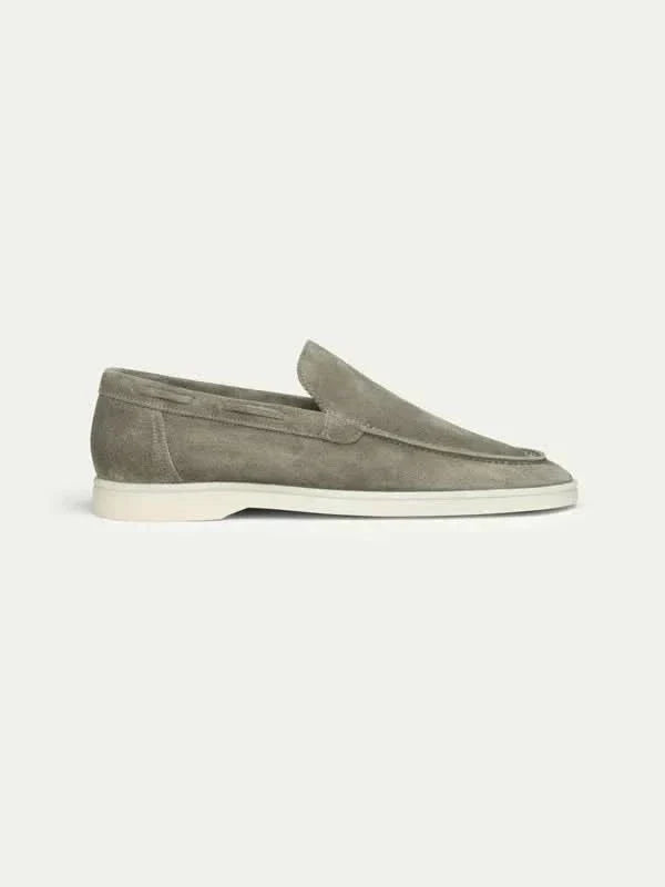 Mocasín de ante gris con suela blanca, diseño clásico sin cordones y bordes marcados.