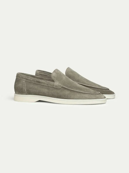 Mocasines de ante color gris topo, estilo slip-on, suela blanca y costuras.