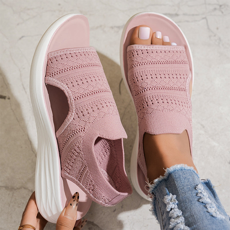 Sandalias ortopédicas de tejido rosa en pies, punta abierta y suela blanca acolchada